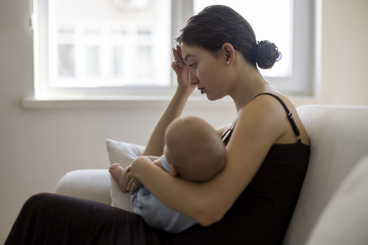A new mother at home holding her sleeping baby